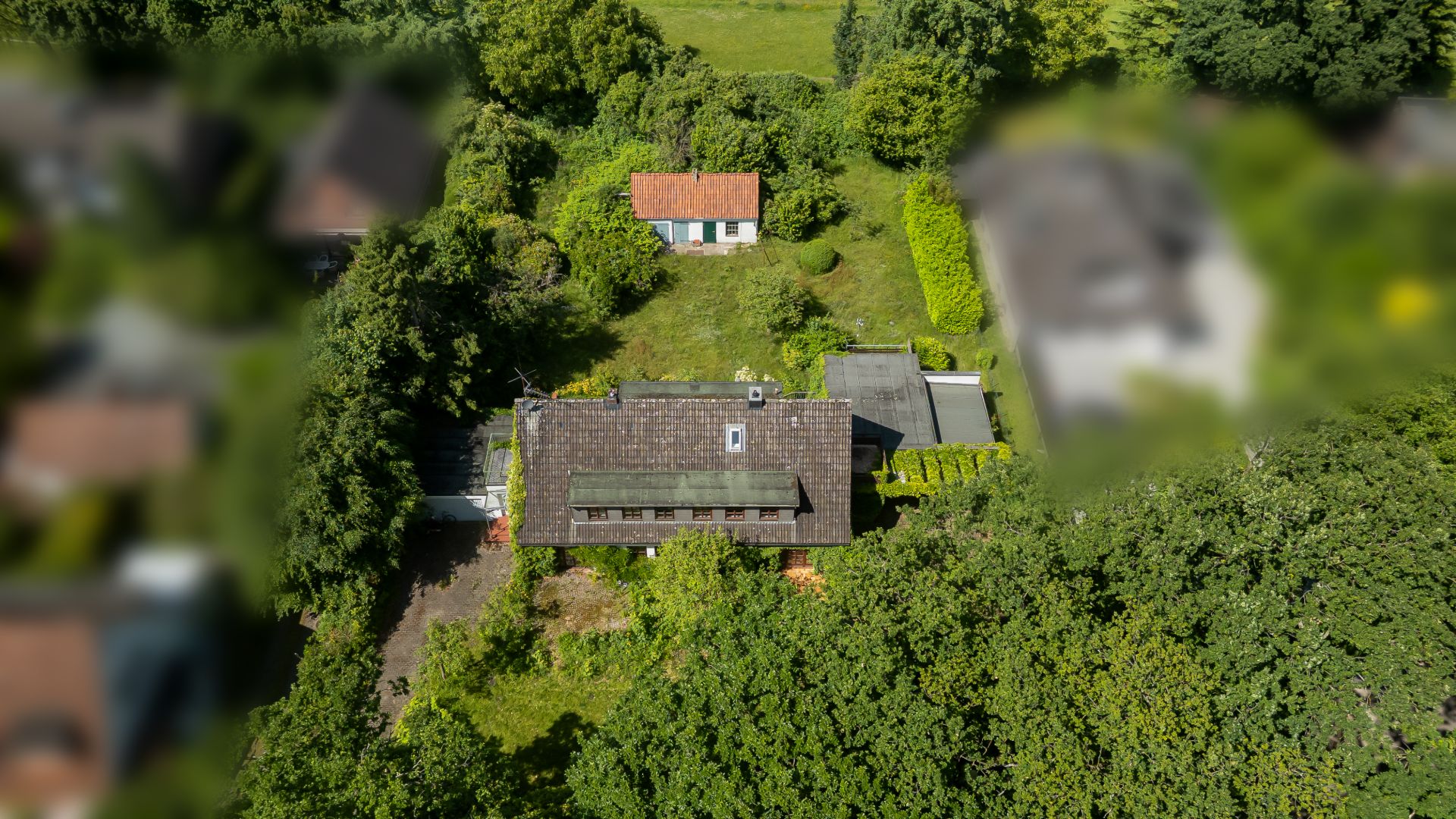 Luftaufnahme eines Wohnhauses mit großem Garten und kleinem Nebengebäude im Grünen.