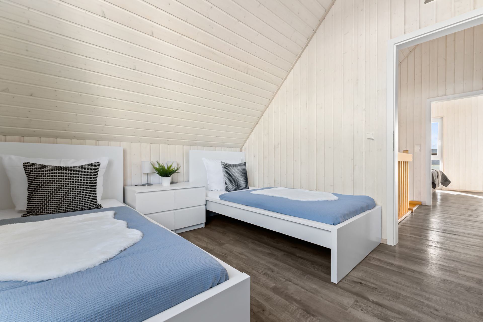 Helles Schlafzimmer mit zwei Einzelbetten, Nachttisch und Holzwänden.