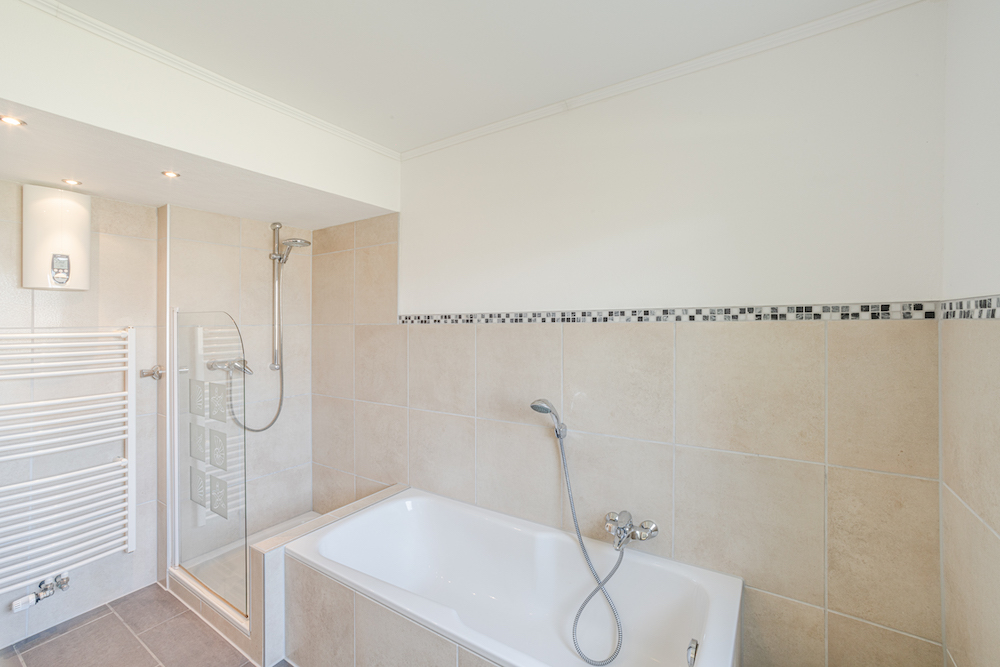 Modernes Badezimmer mit Badewanne, Dusche und Handtuchheizkörper.