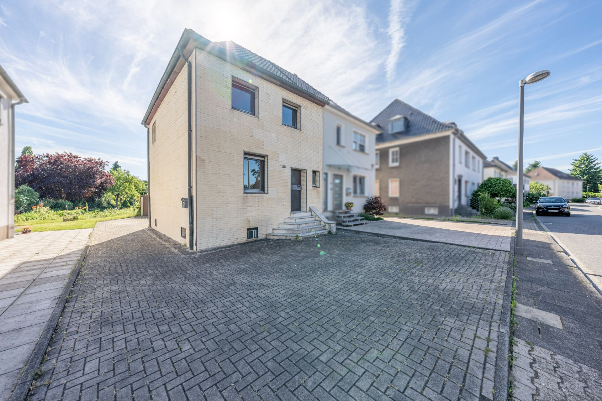 Einfamilienhaus mit gepflasterter Einfahrt und kleiner Treppe am Eingang.