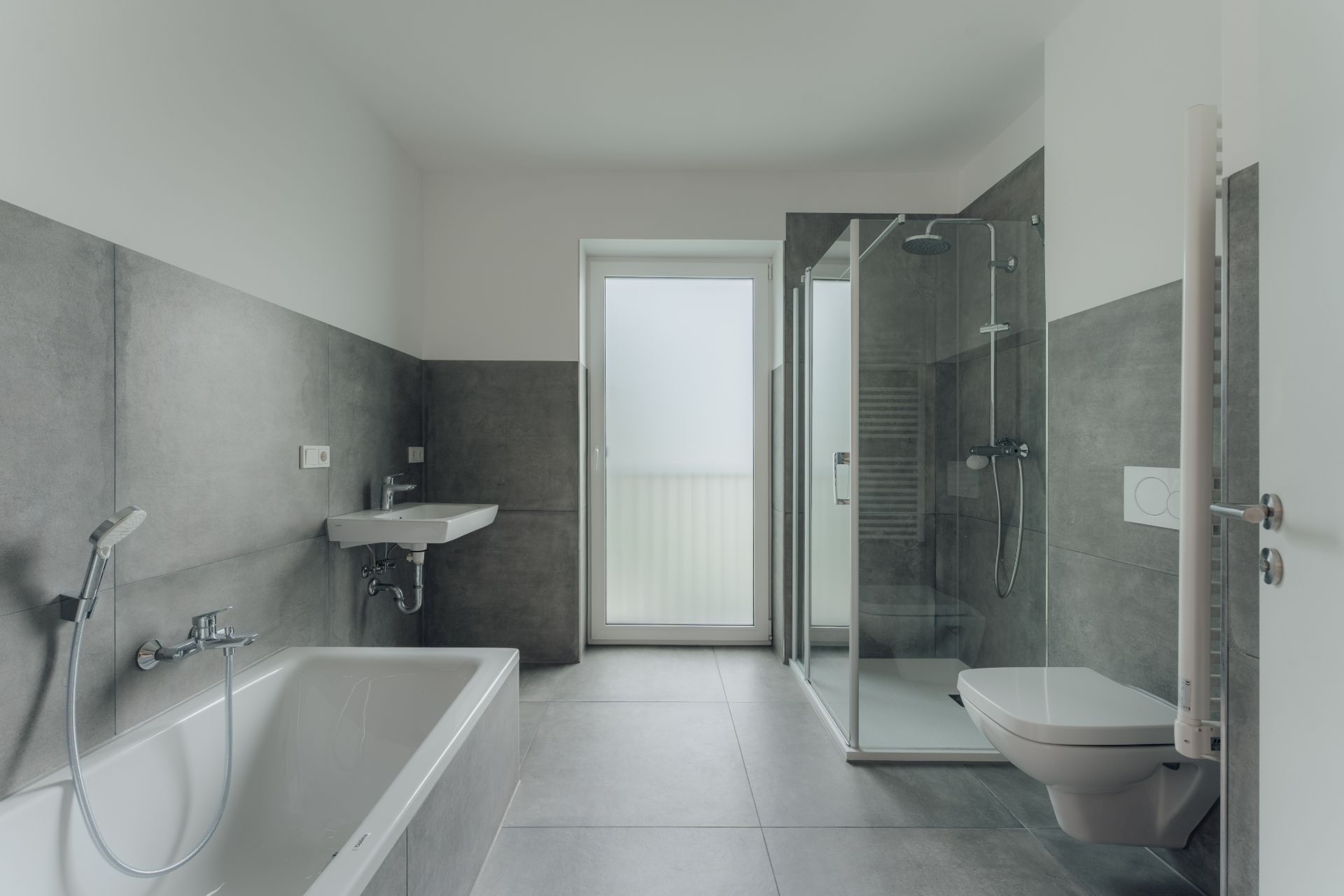 Modernes Badezimmer mit Badewanne, Dusche, Waschbecken und Wandtoilette.