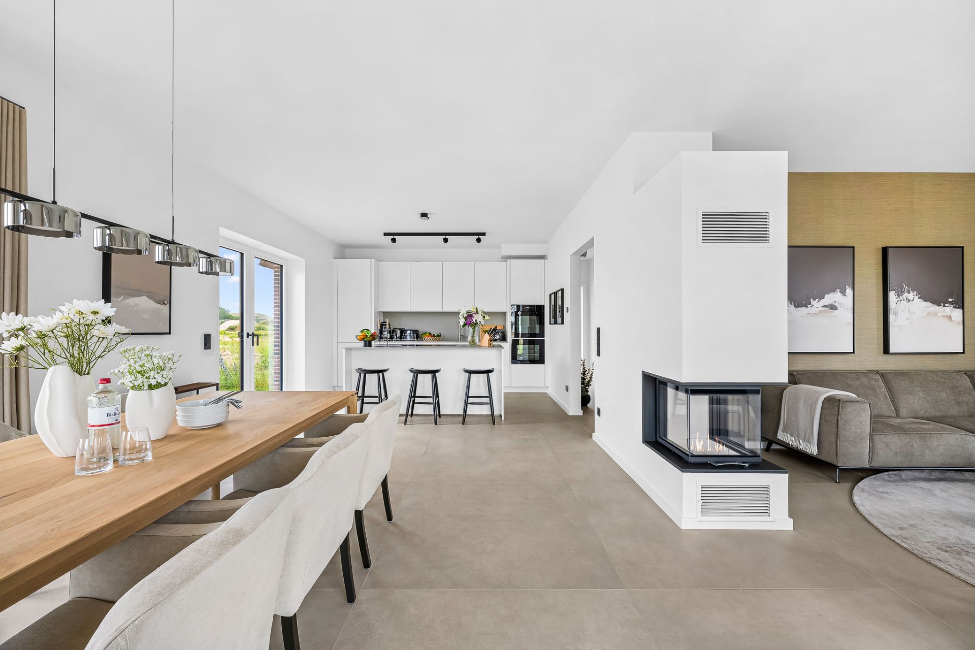 Modernes Wohnzimmer mit Essbereich, Kamin, offener Küche und großen Fenstern.