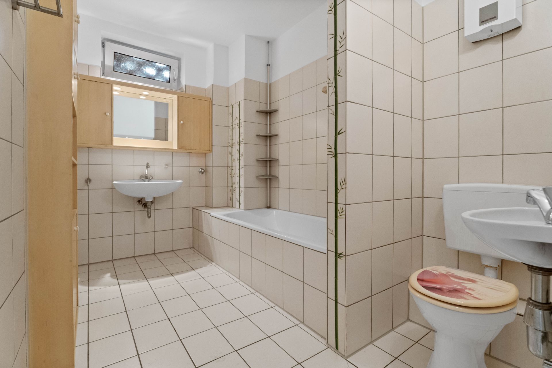 Helles Badezimmer mit Badewanne, Waschbecken, Toilette und Spiegelschrank.