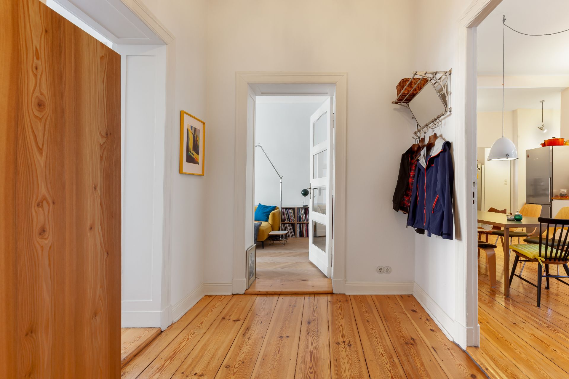 Heller Flur mit Holzboden, Garderobe an der Wand und Blick ins Wohnzimmer und Esszimmer.