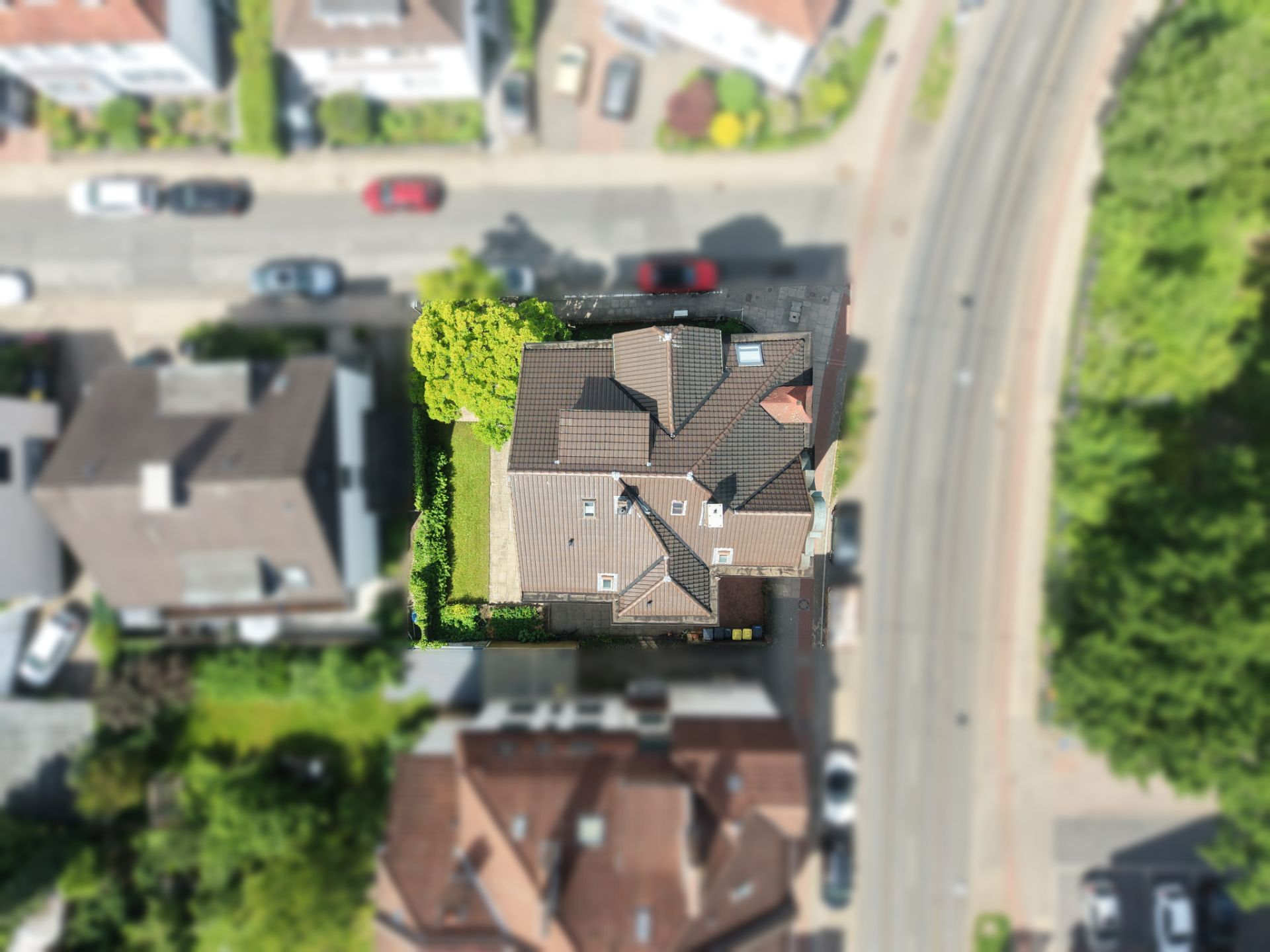 Luftaufnahme eines Einfamilienhauses mit Garten und umliegenden Straßen.