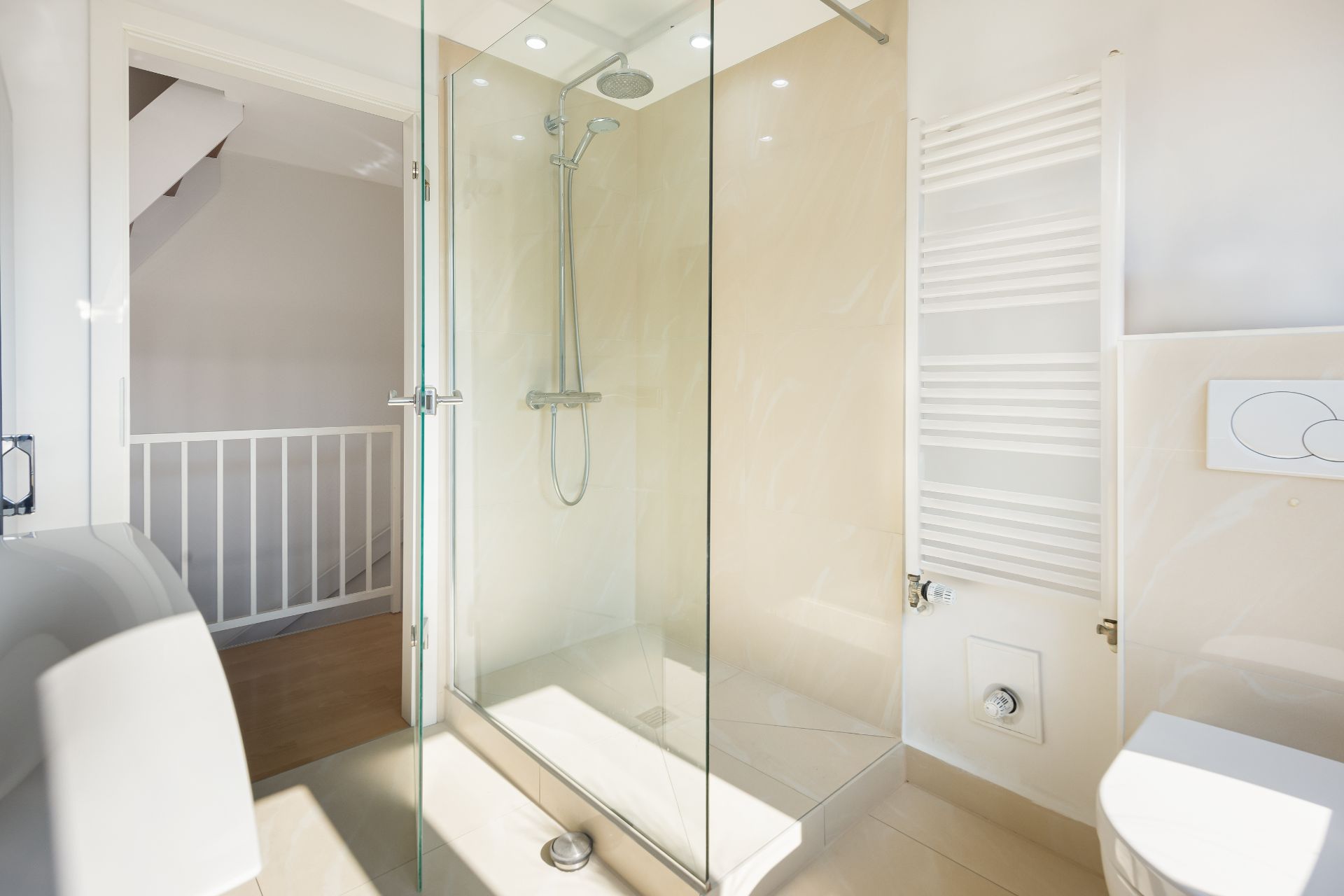 Modernes Badezimmer mit Glasdusche, weißem Handtuchheizkörper und WC.