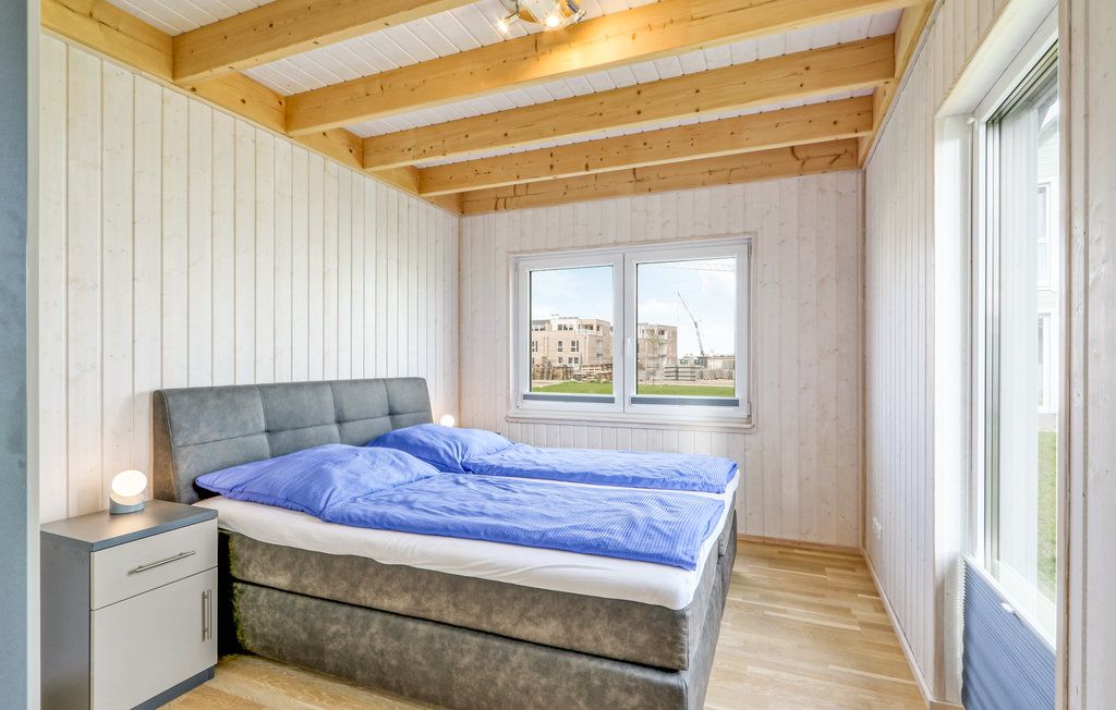 Helles Schlafzimmer mit Doppelbett, Nachttischen und großen Fenstern, Holzwände und sichtbare Deckenbalken.
