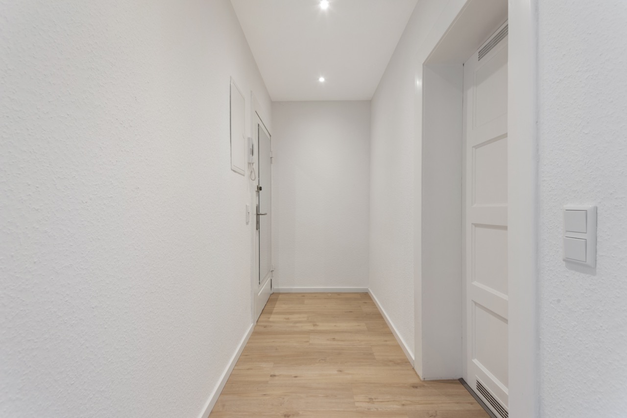 Heller Flur mit Holzboden, weißen Wänden und weißen Türen.