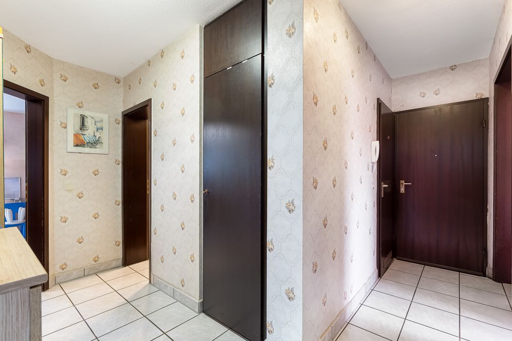 Flur mit dunklen Holztüren, Einbauschrank und gemusterter Tapete.