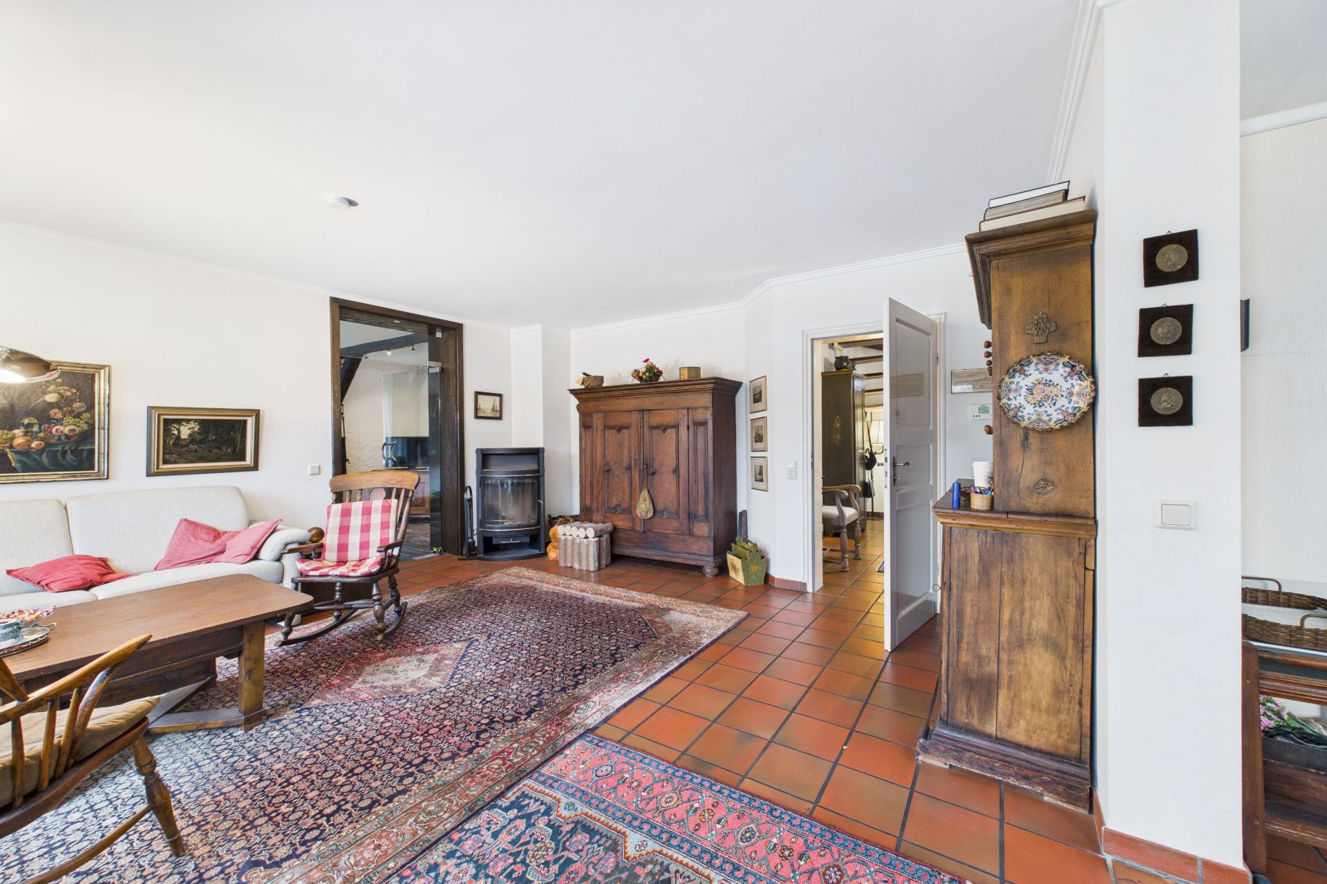 Wohnzimmer mit Holzmöbeln, Teppichen, Sofa und gemusterten Fliesenboden.