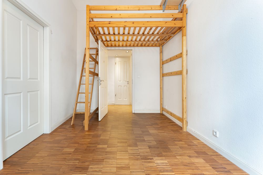 Leeres Zimmer mit Hochbett aus Holz, Parkettboden und weißer Wand.