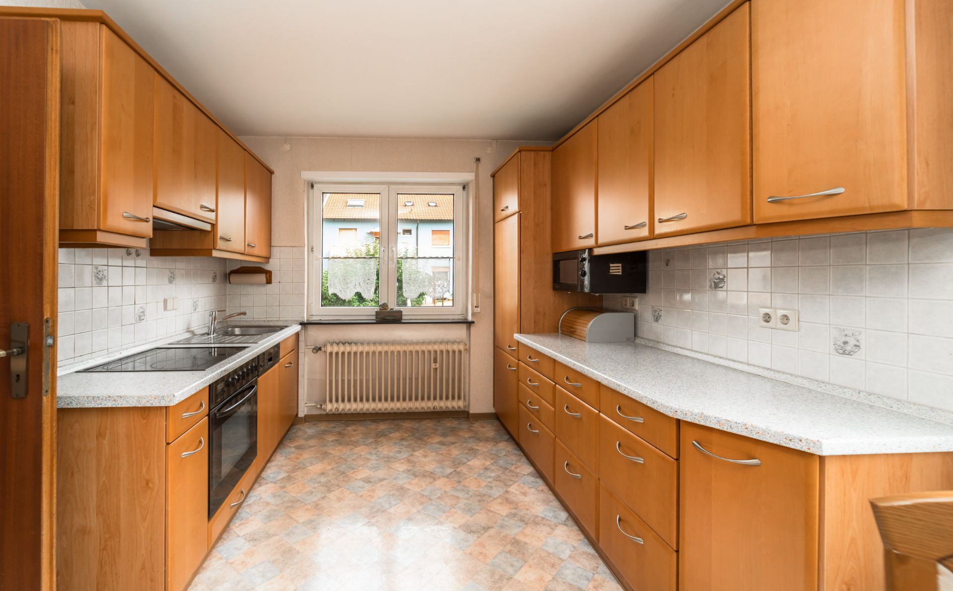 Helle Einbauküche mit Holzfronten, Herd, Spüle und Fenster zur Gartenseite.