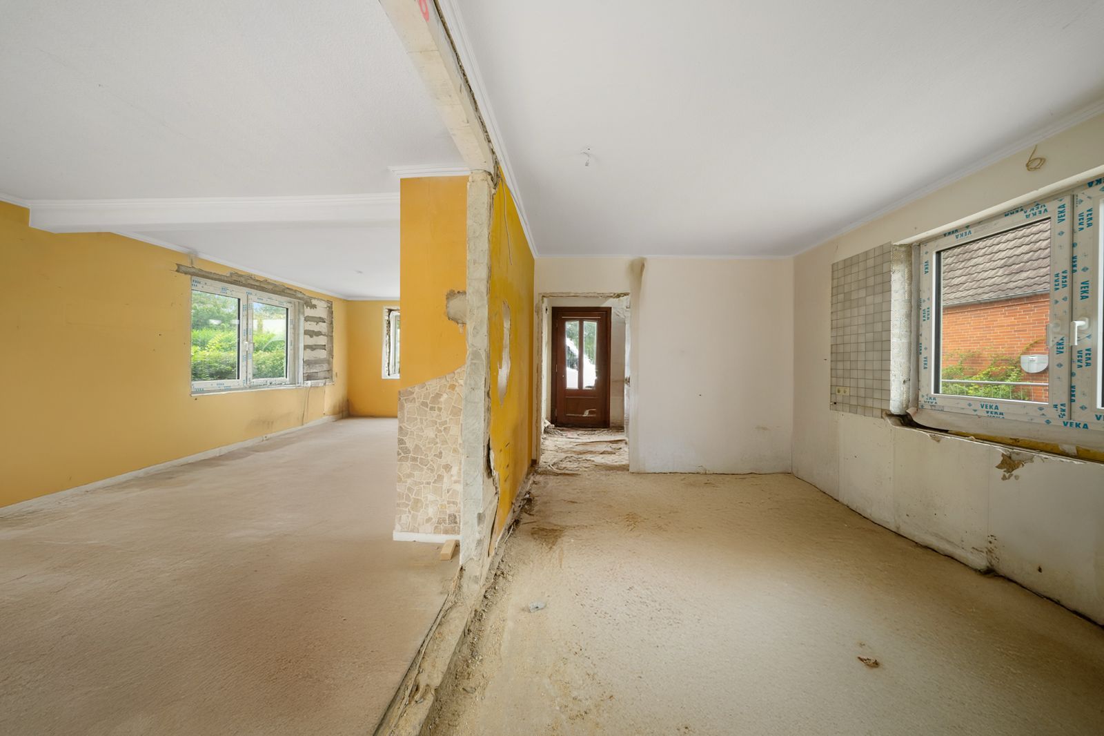 Wohnraum mit gelber Wand, sichtbarer Bausubstanz und renovierungsbedürftigem Zustand.
