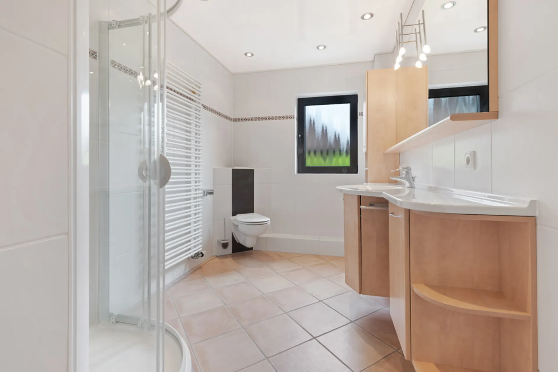 Helles Bad mit Dusche, WC, großem Spiegel und Holzwaschtisch, gefliester Boden.