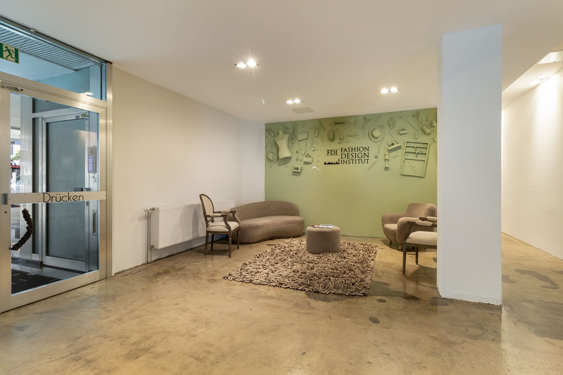 Heller Raum mit Sitzgruppe, Teppich und Glastür. An der Wand Dekoration und Heizkörper.