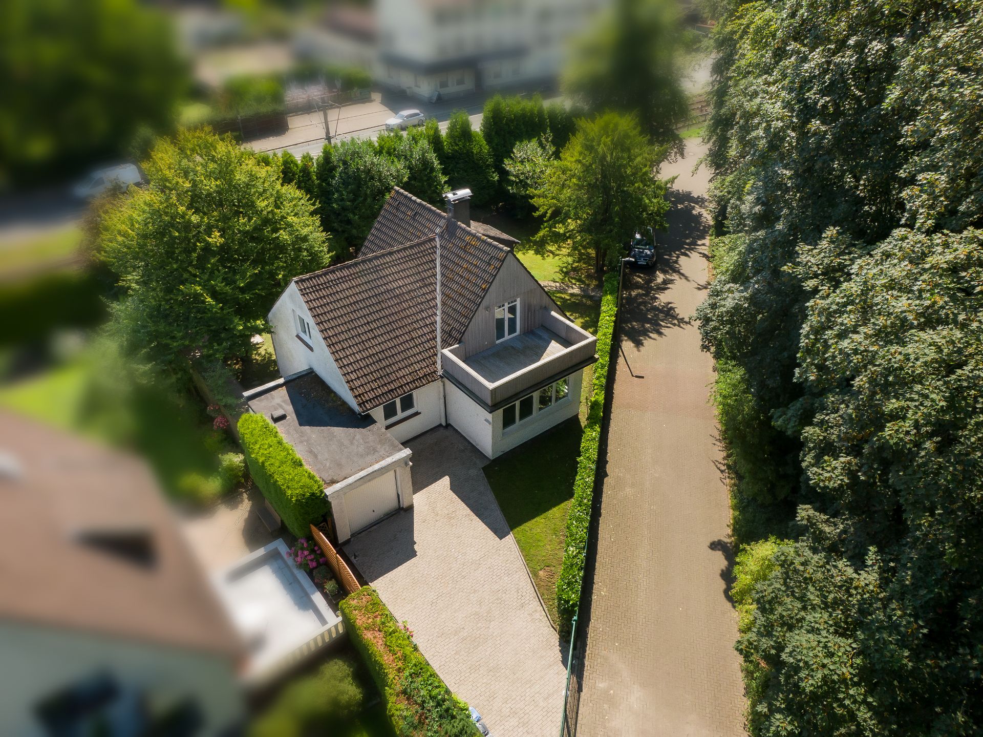Luftaufnahme eines freistehenden Einfamilienhauses mit Auffahrt und Garten.