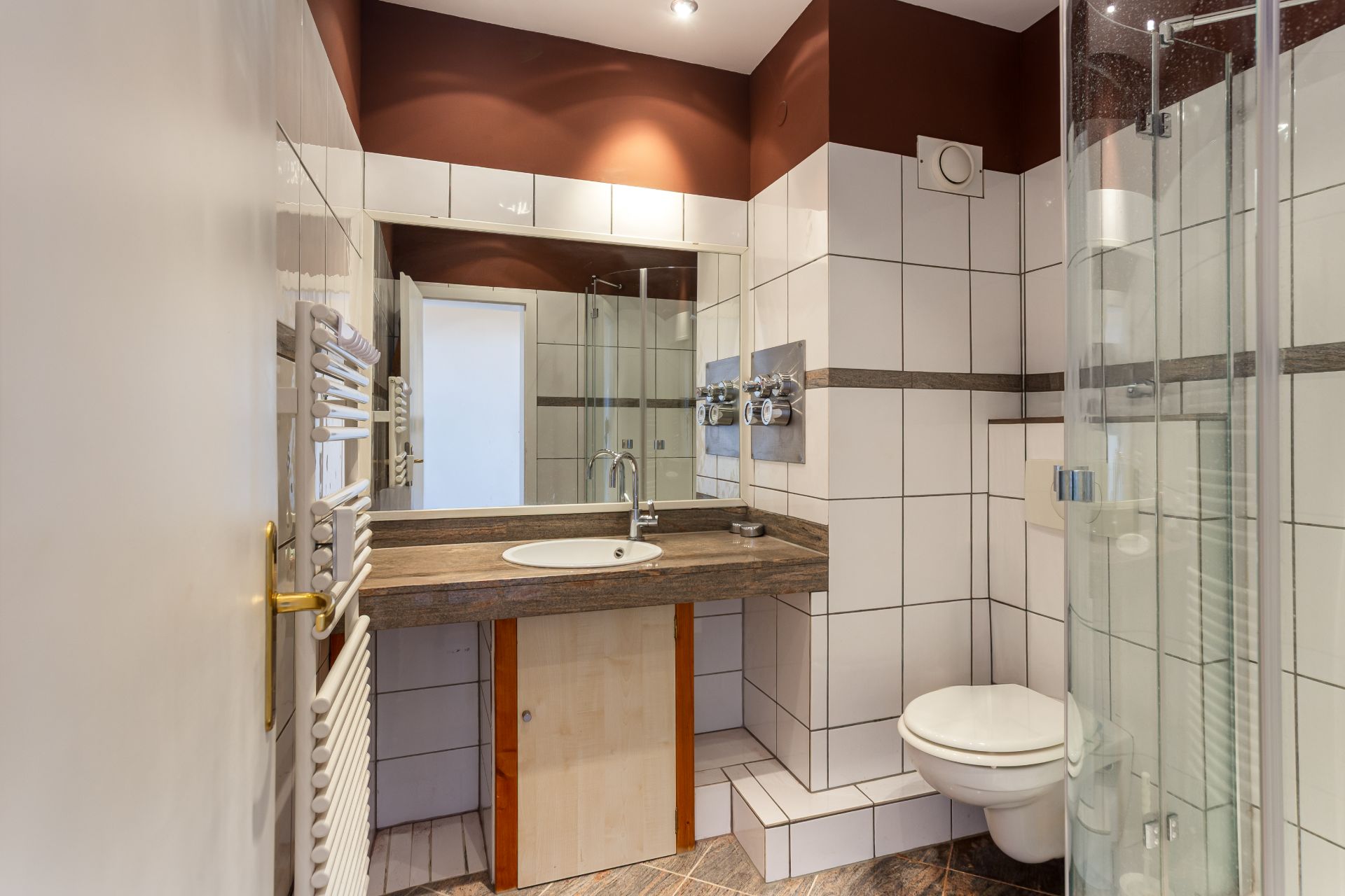 Modernes Badezimmer mit Waschbecken, Spiegel, Dusche und Wandtoilette.