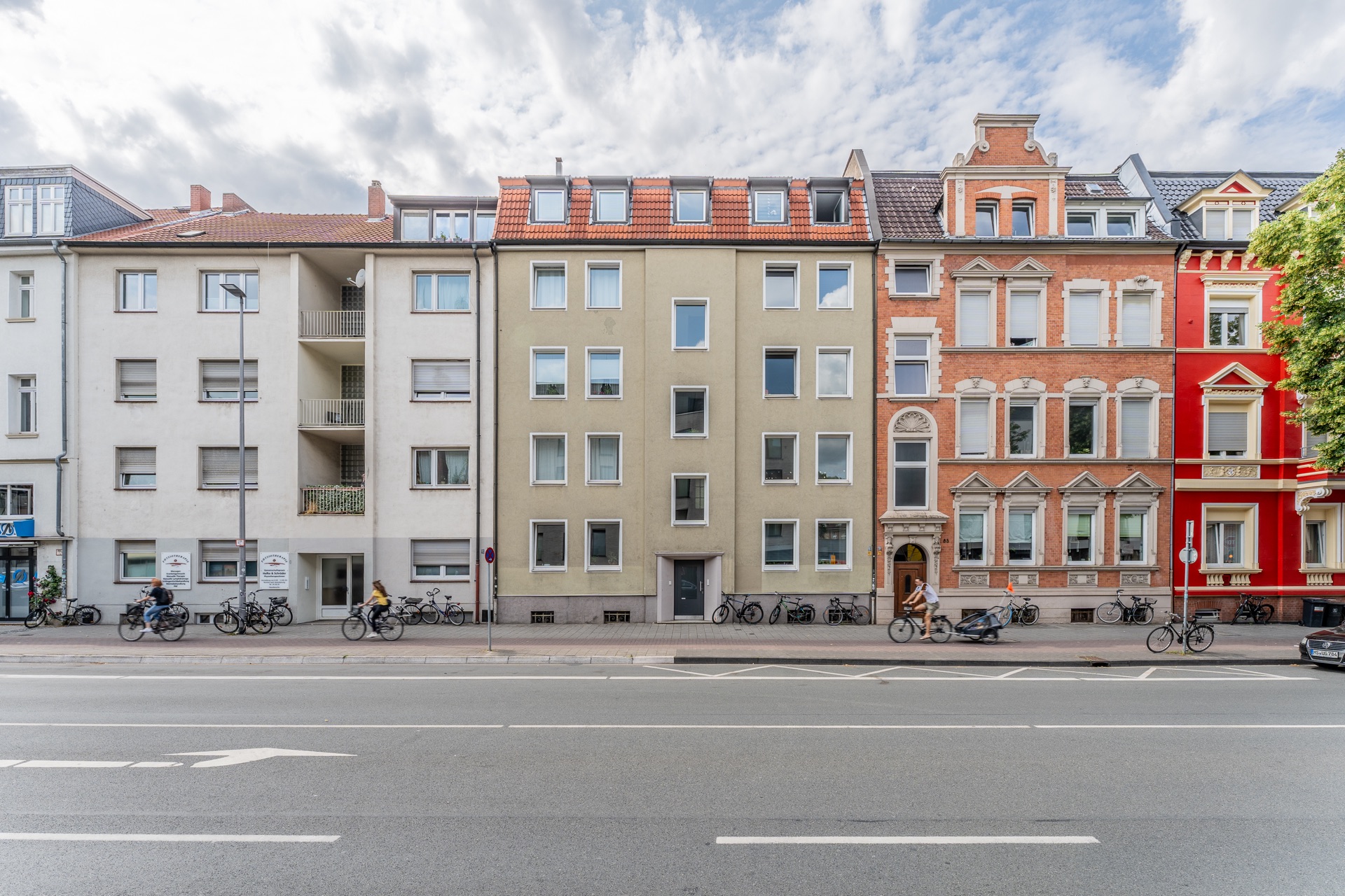 Mehrstöckige Wohnhäuser mit Fahrrädern vor den Eingängen an einer Straßenfront.