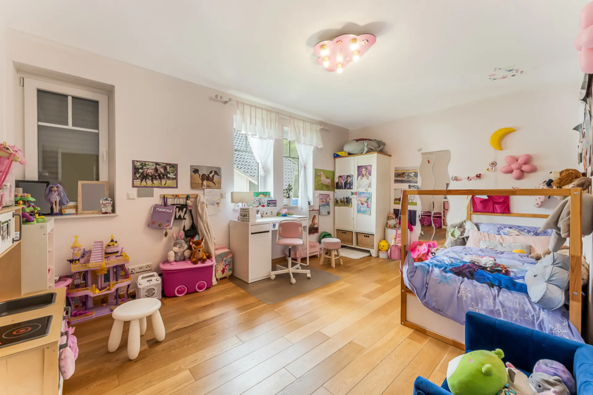 Helles Kinderzimmer mit Spielzeug, Schreibtisch, Bett und Holzfußboden.