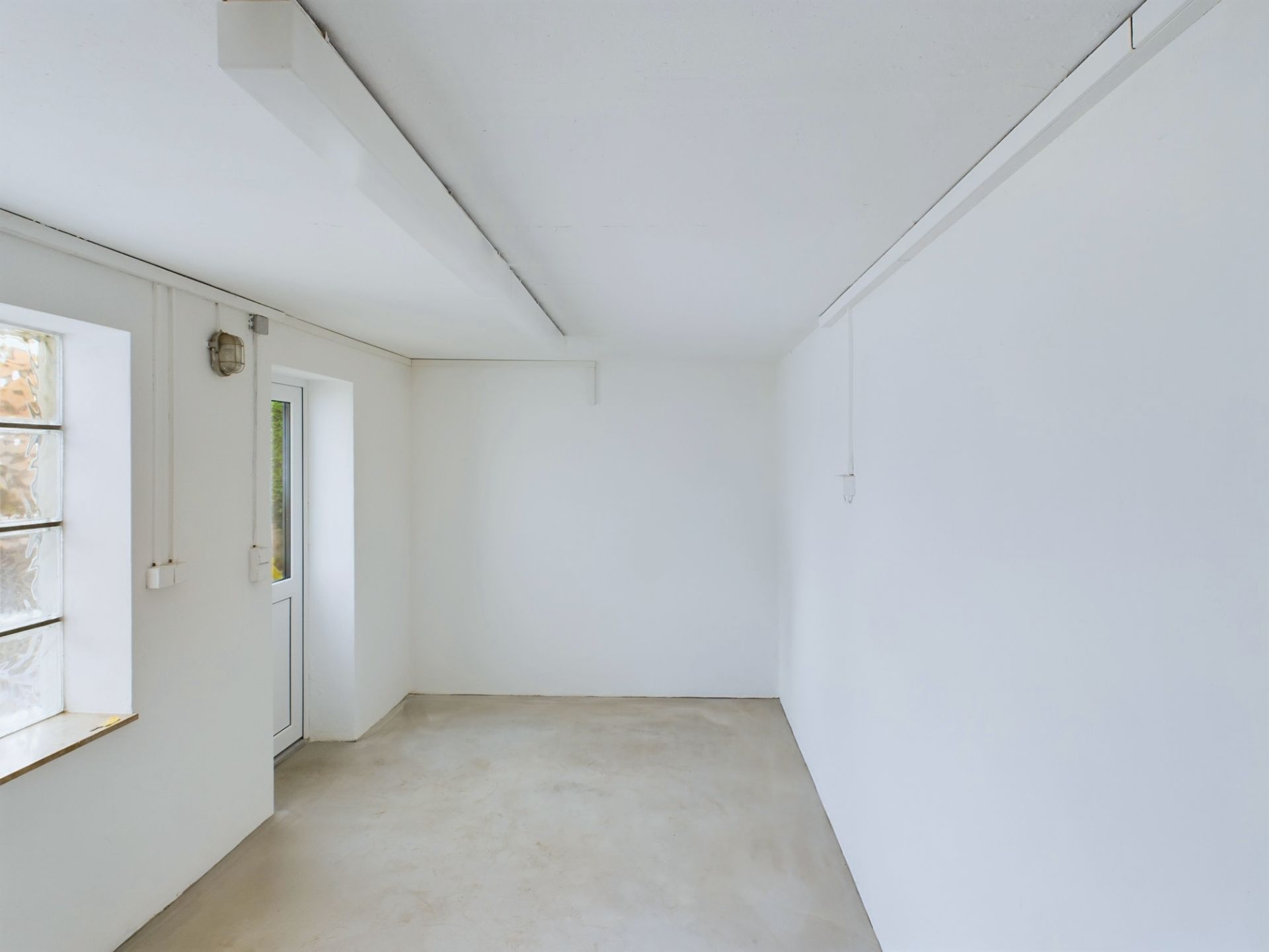 Leerer Raum mit weißen Wänden, Fenster und Tür, einfacher Betonboden.