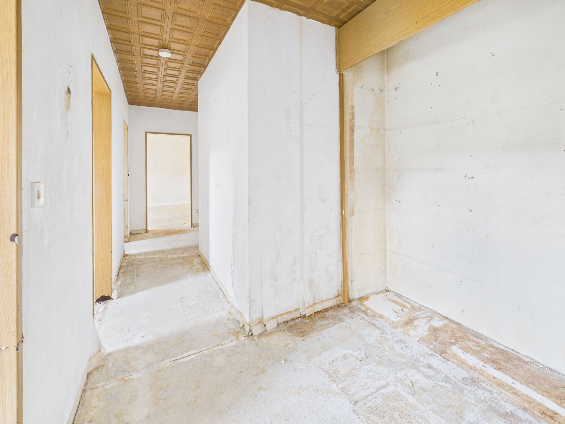 Leerer Flur mit weiß gestrichenen Wänden und ohne Bodenbelag in einer Wohnung.