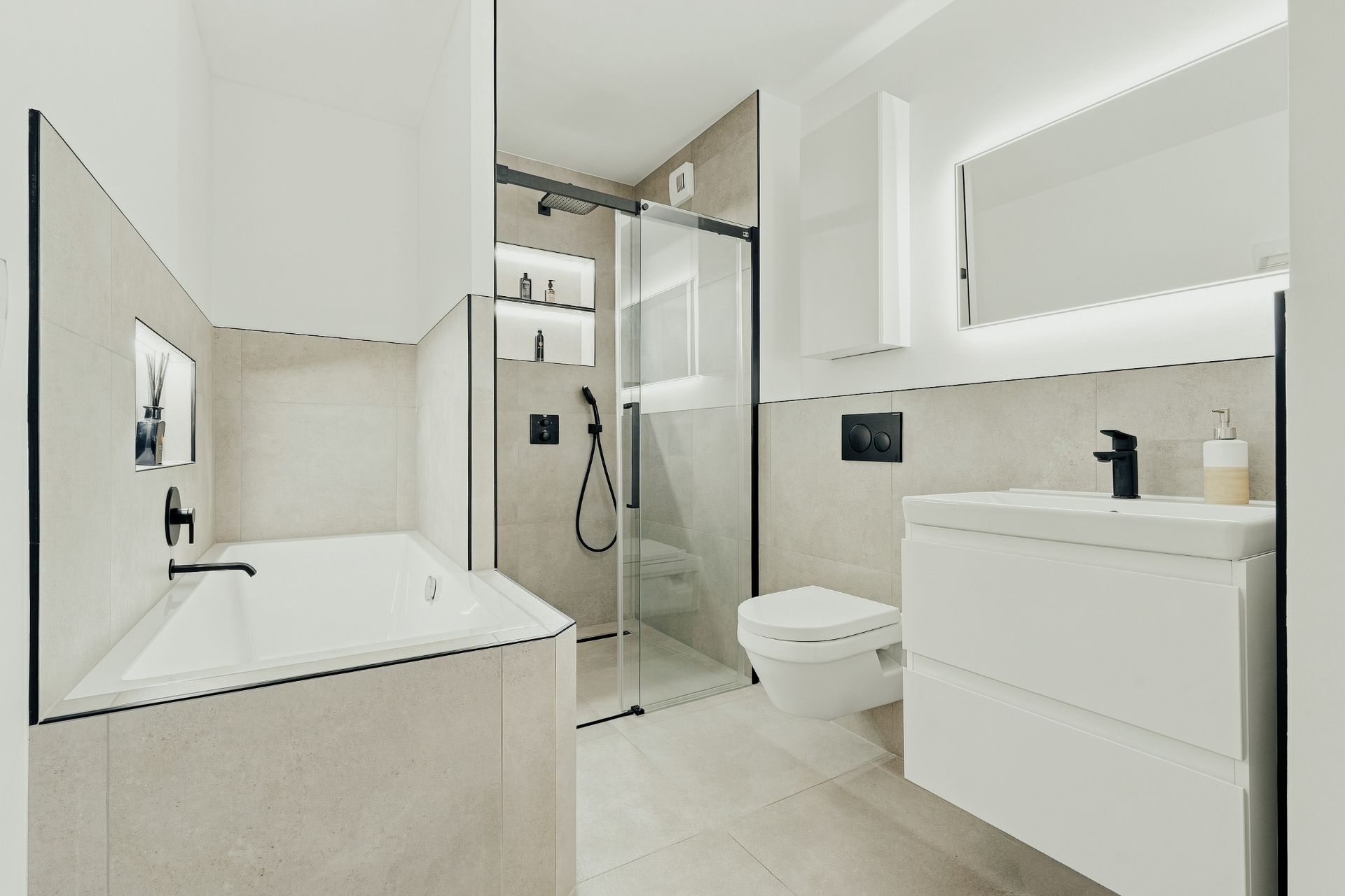 Modernes Badezimmer mit Badewanne, Dusche, Wandtoilette und Waschtisch mit Spiegel.