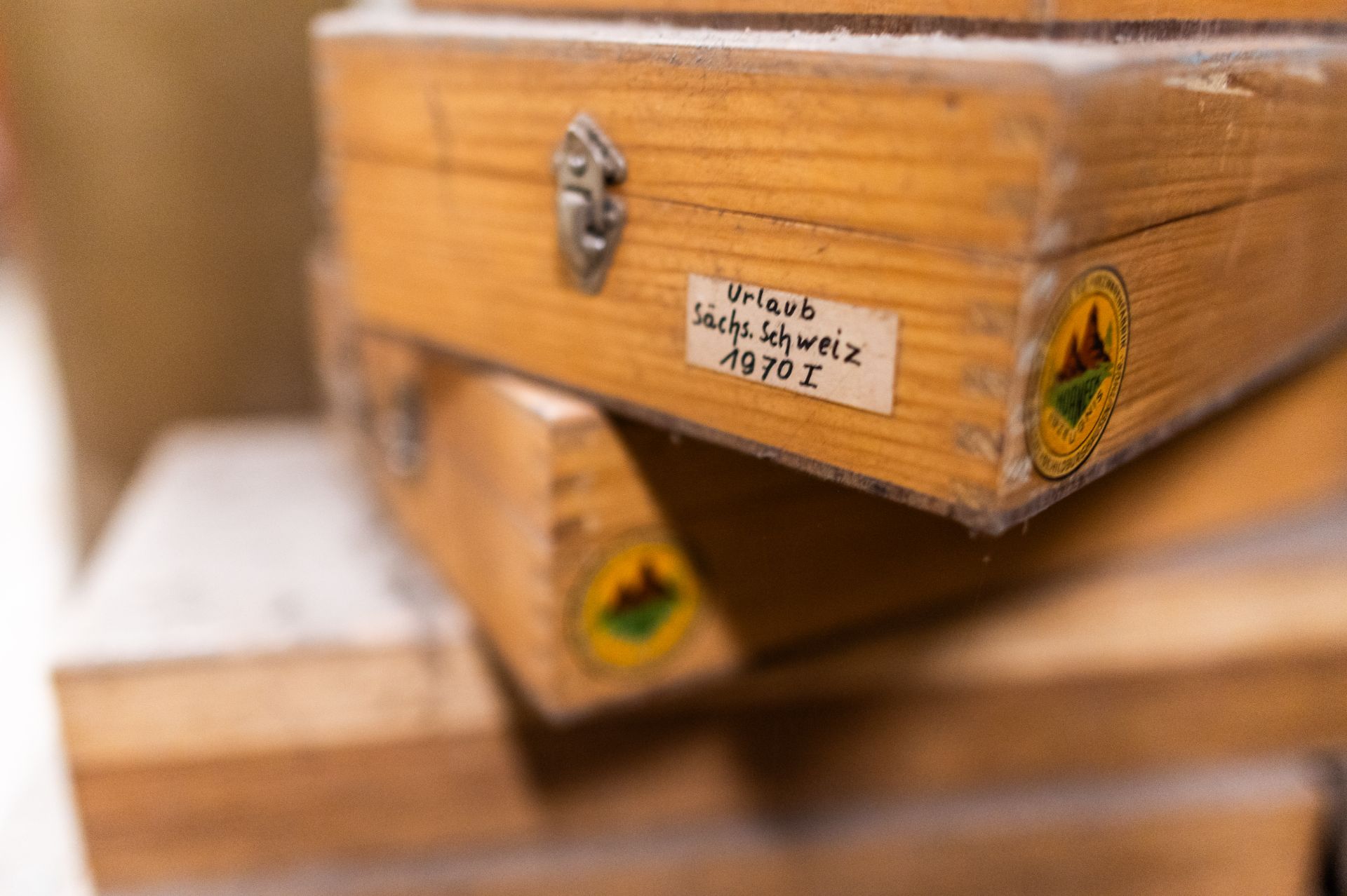 Nahaufnahme von gestapelten Holzkisten mit Aufklebern und einem handschriftlichen Etikett.