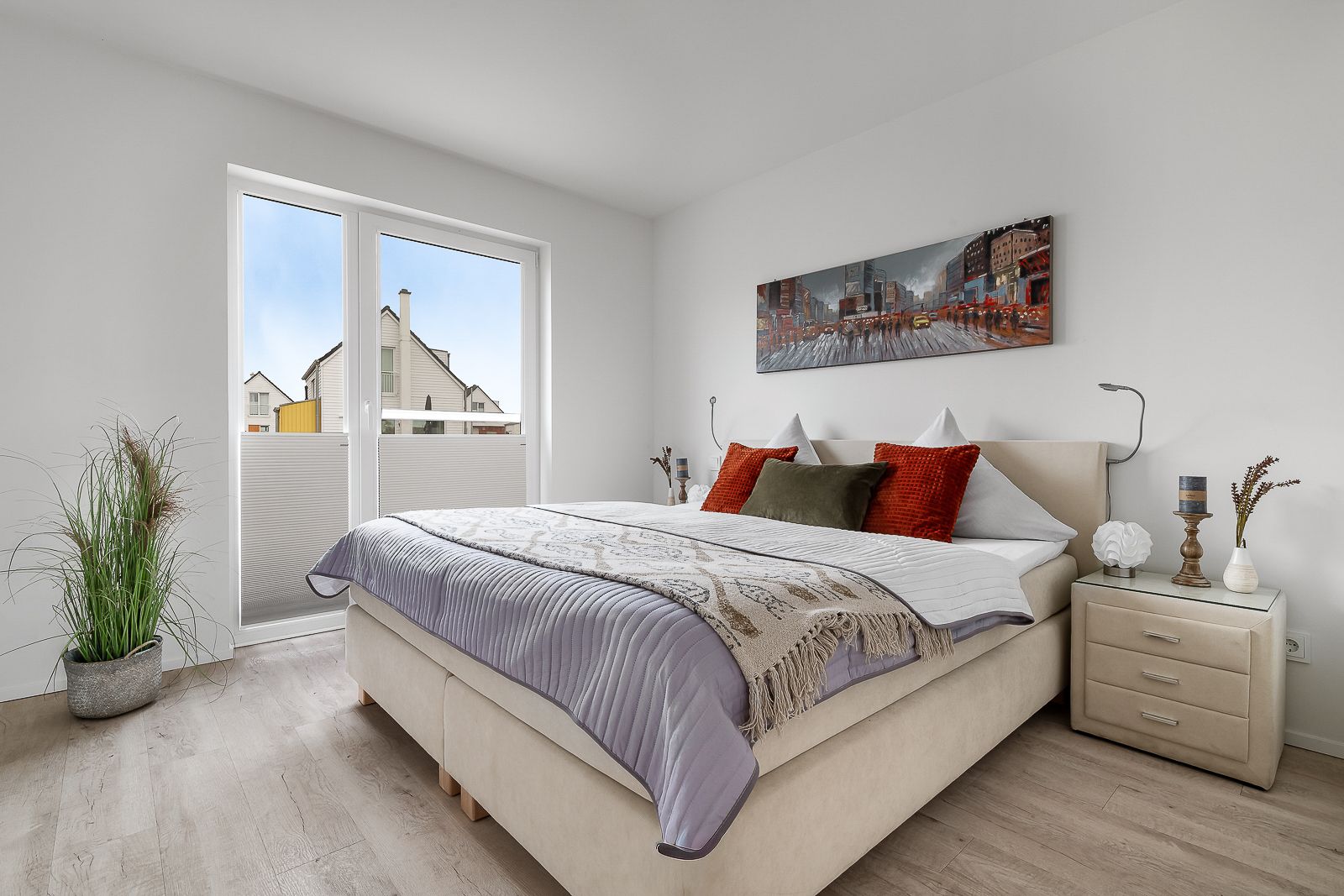 Helles Schlafzimmer mit Doppelbett, Nachttischen, großem Fenster und Wandbild.