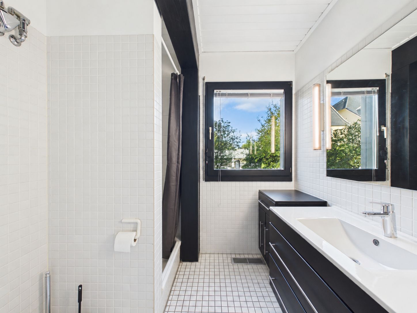 Modernes Badezimmer mit großem Fenster, Waschbecken, Spiegel und Dusche mit weißem Fliesendekor.