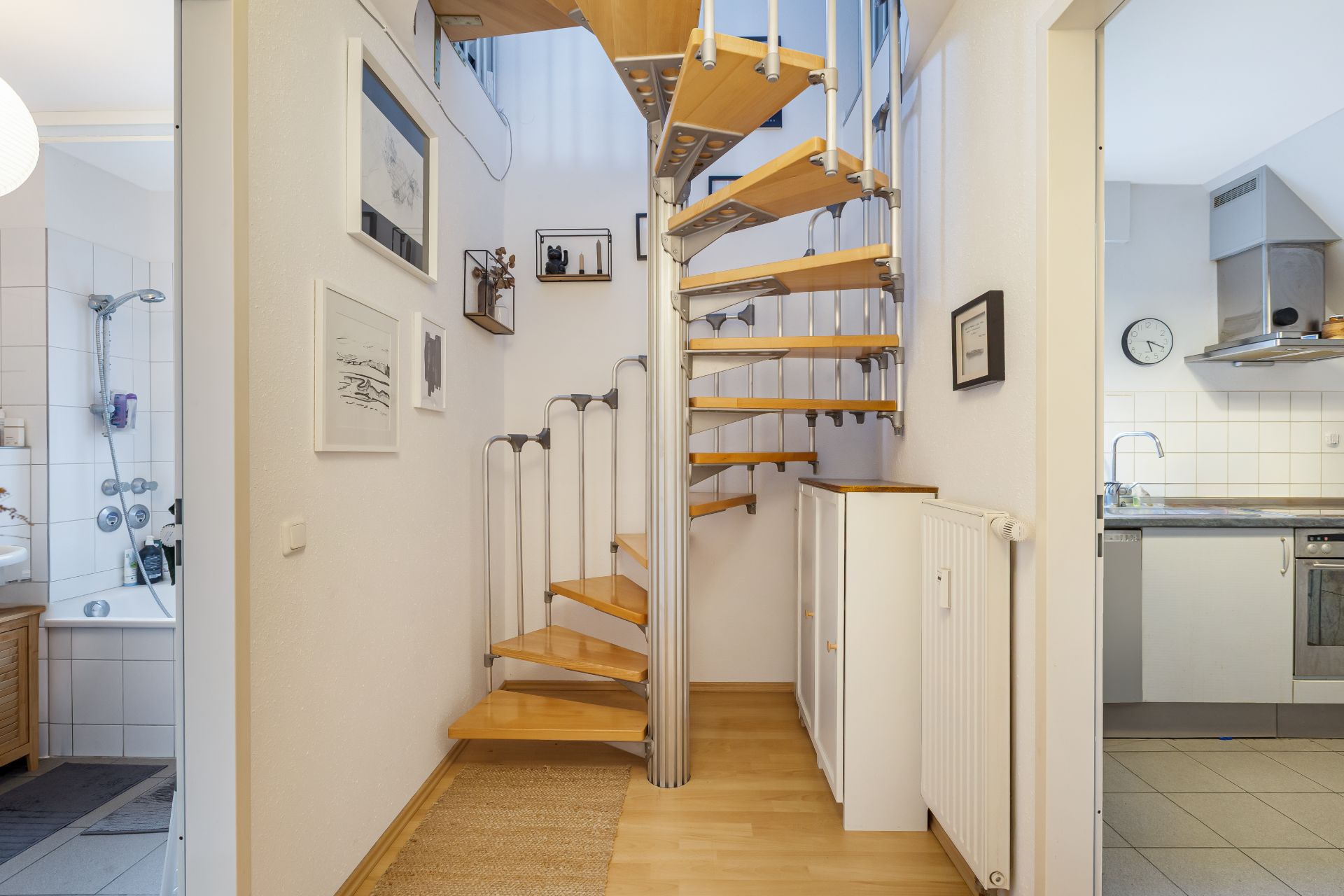 Moderne Holz-Wendeltreppe neben Flur, mit Zugang zum Badezimmer und zur Küche.
