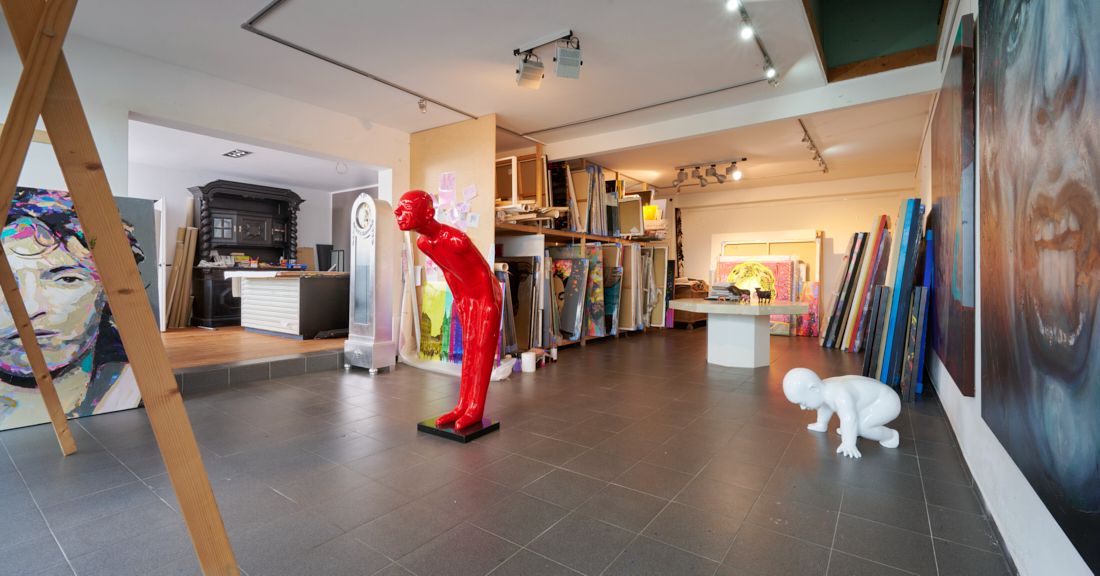 Großer Raum mit Kunstwerken, Gemälden an den Wänden und zwei farbigen Skulpturen.