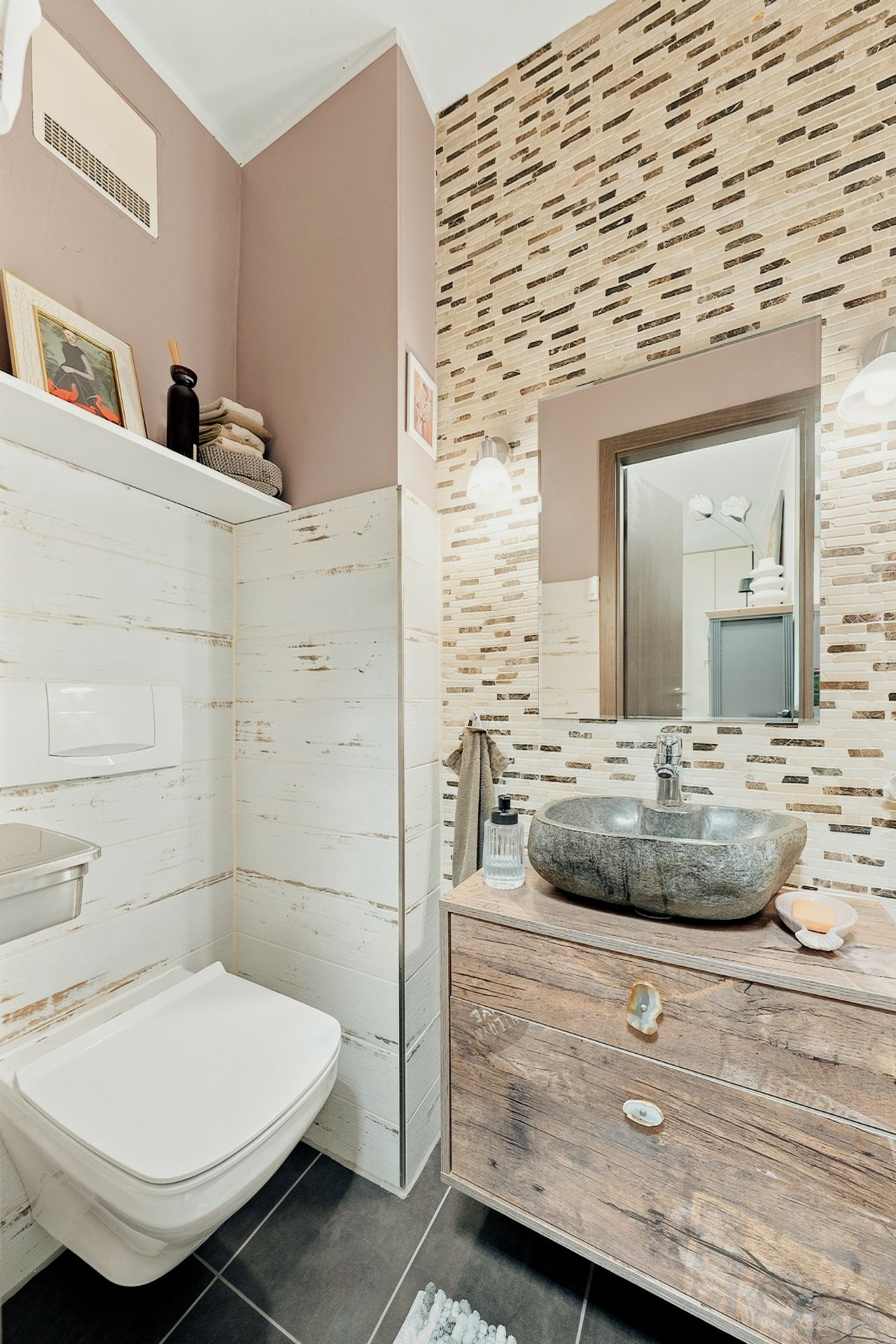 Modernes Bad mit Wand-WC, Steinwaschbecken, Holzschrank und gemusterter Wand.