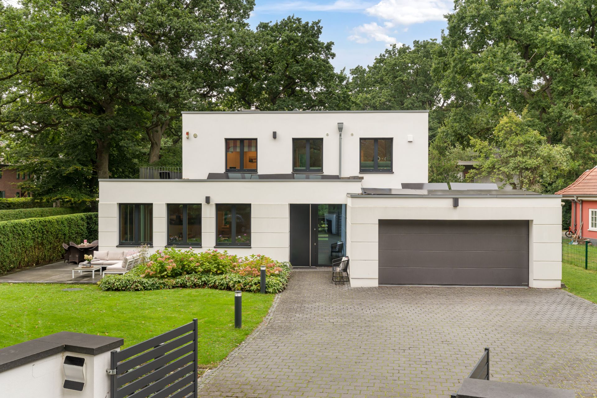 Modernes zweistöckiges Wohnhaus mit großer Einfahrt, Garage und gepflegtem Garten.