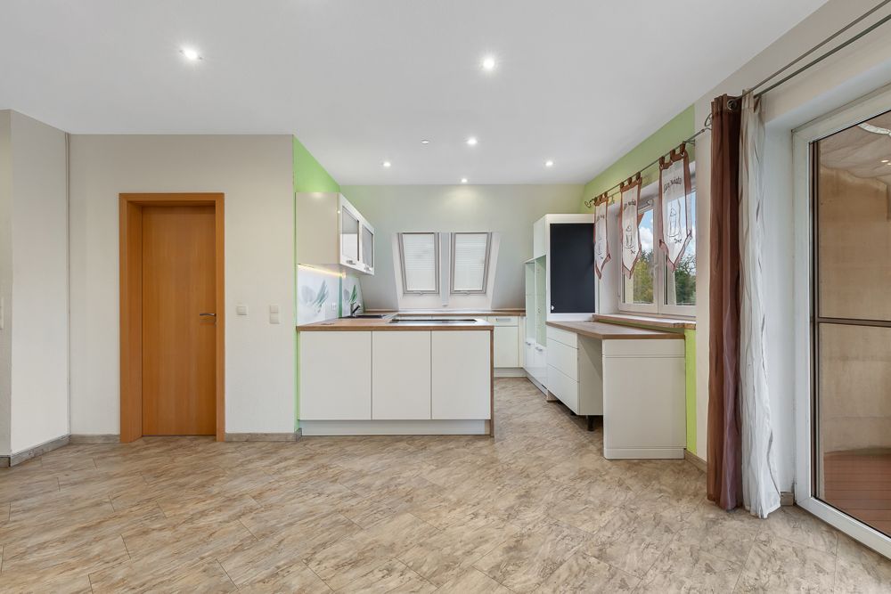 Moderne, helle Einbauküche mit Holzdetails und großen Fenstern, Blick auf Fliesenboden.