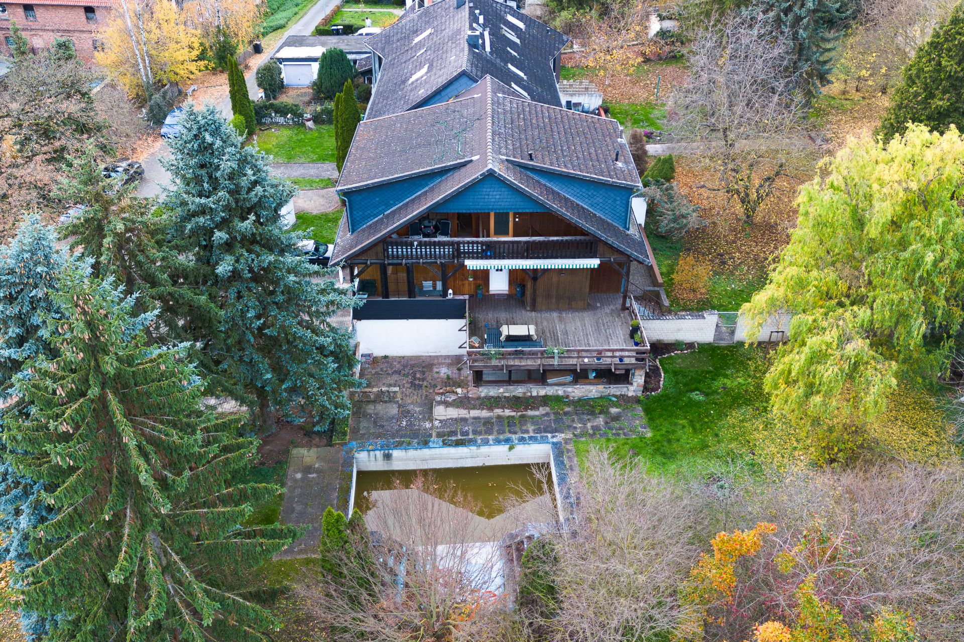 Luftaufnahme eines Wohnhauses mit Terrasse, Garten und kleinem Swimmingpool, umgeben von Bäumen.