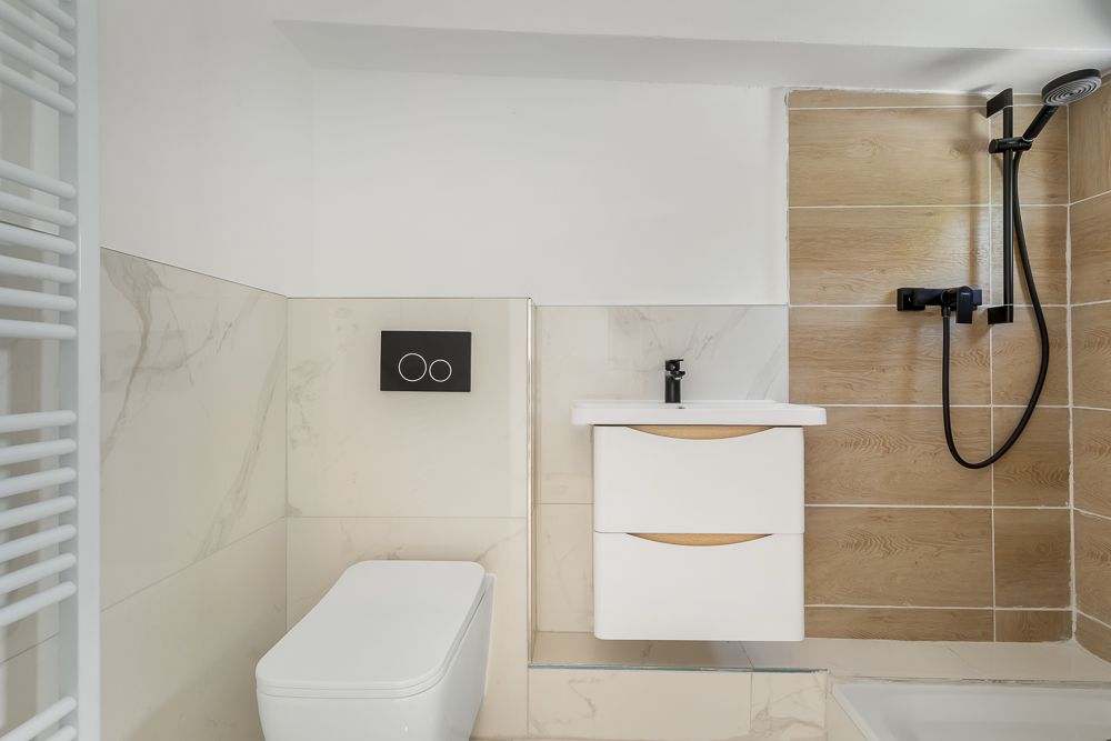 Modernes Badezimmer mit WC, Waschbecken und Dusche mit Holz- und Marmorfliesen.