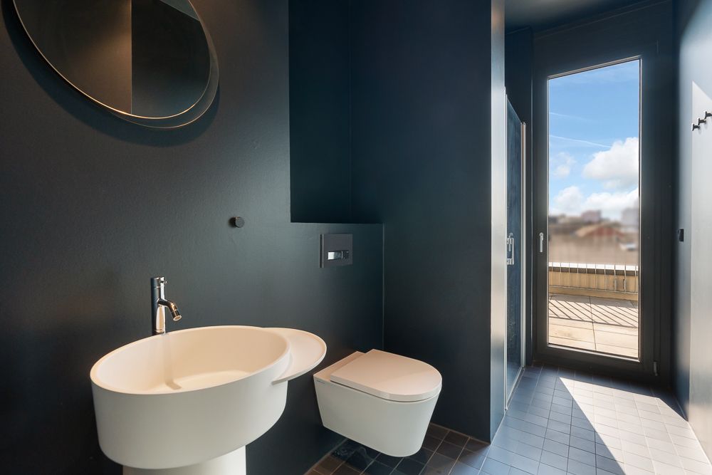 Modernes Bad mit Waschbecken, WC und großem Fenster mit Blick nach draußen.