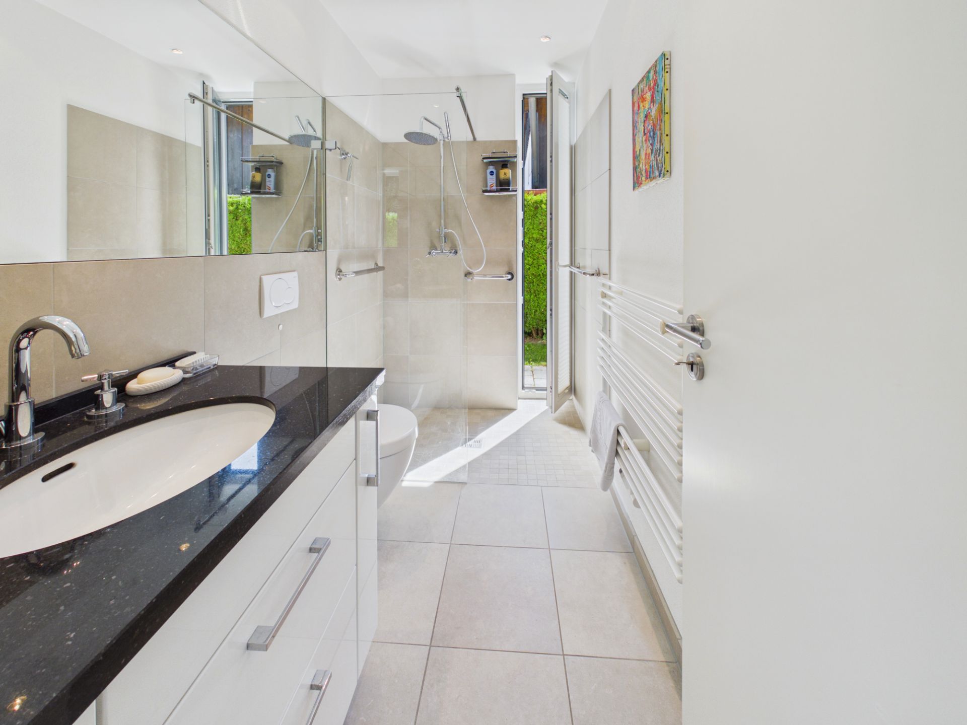 Modernes Badezimmer mit Dusche, Waschbecken, Toilette und Tageslicht von Außentür.