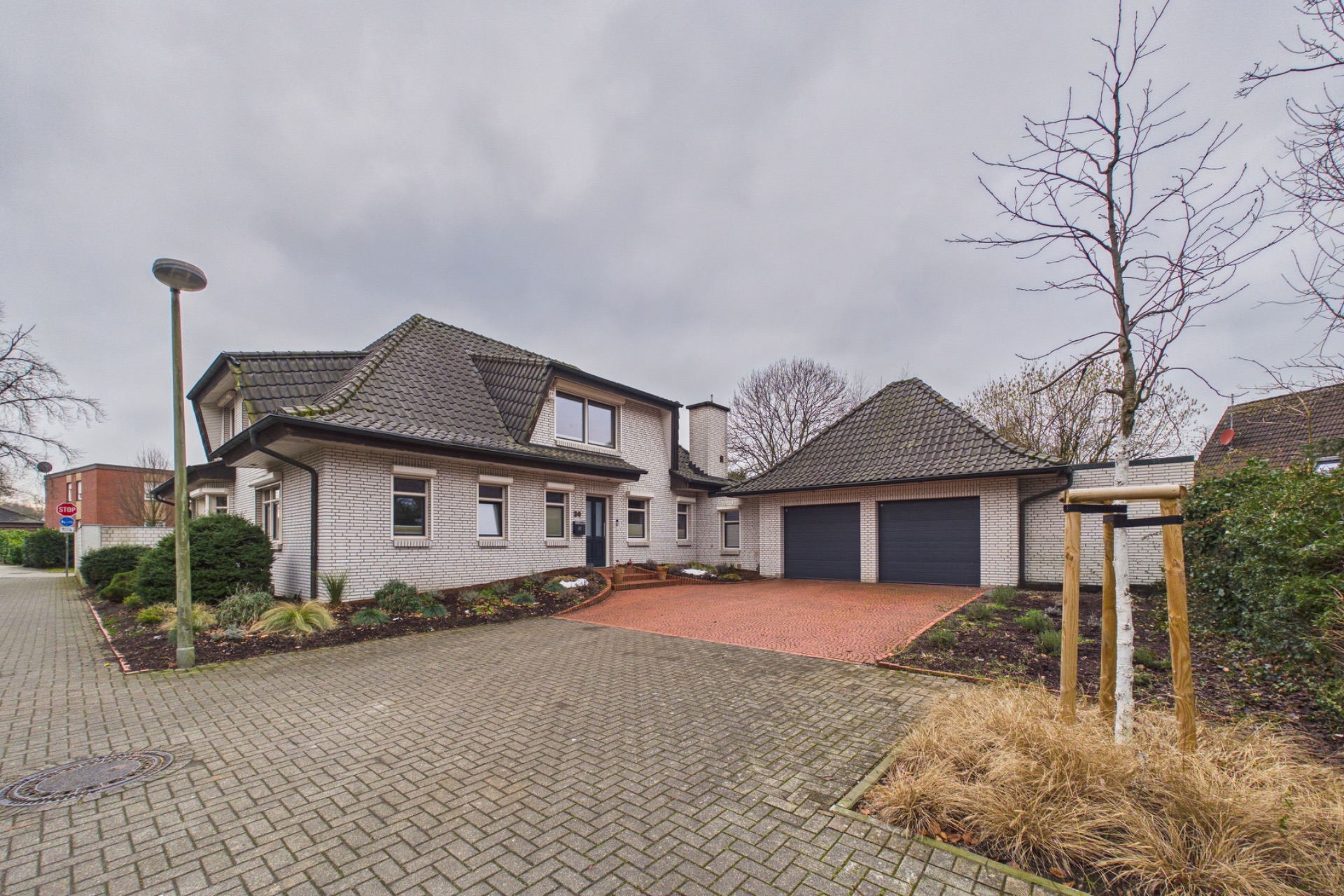 Zweistöckiges Wohnhaus mit Doppelgarage, gepflasterter Einfahrt und Garten.