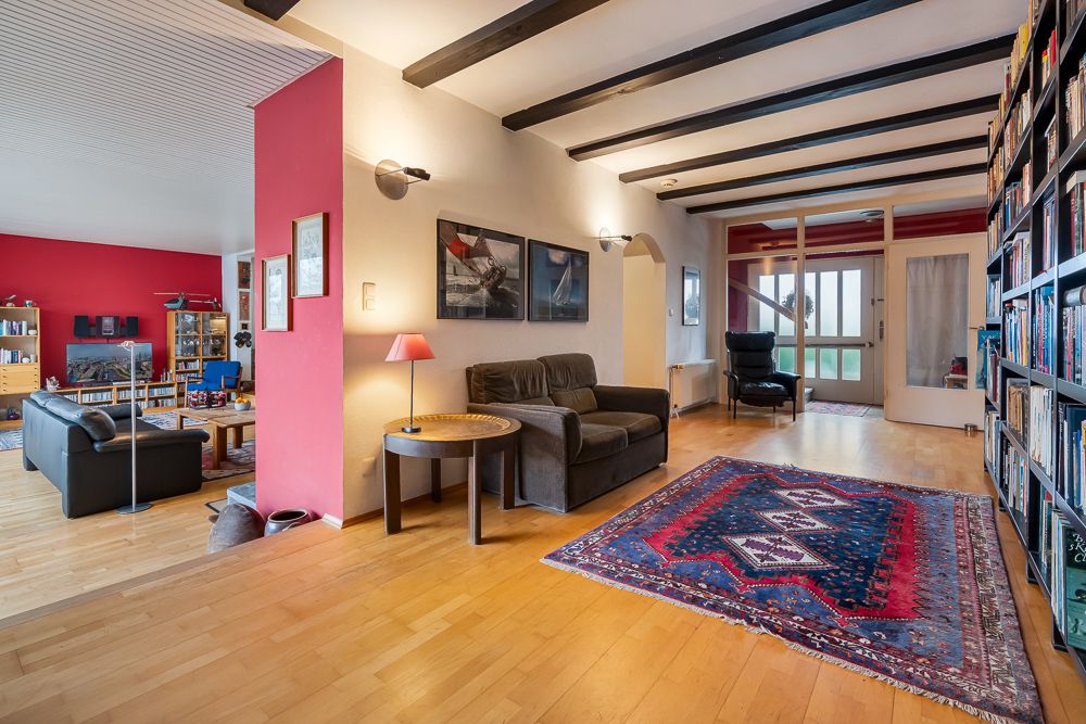 Wohnzimmer mit Holzboden, Teppich, Sofa, Bücherregal und moderner Einrichtung.