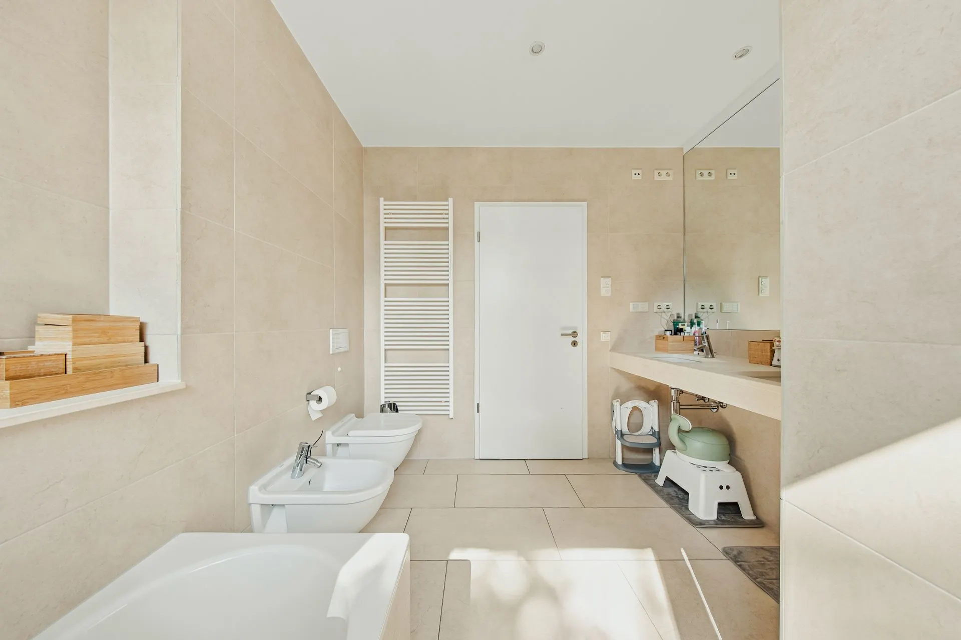 Modernes Badezimmer mit Badewanne, Bidet, WC, Waschbecken und großem Spiegel.