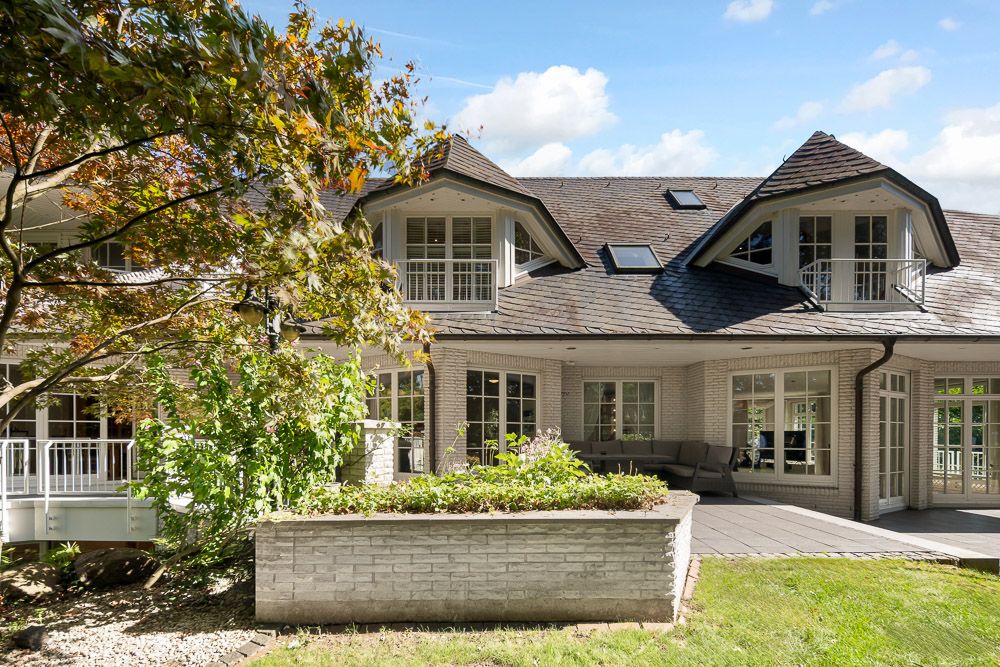 Zweistöckiges Haus mit Balkonen, großen Fenstern und Terrasse im Garten.