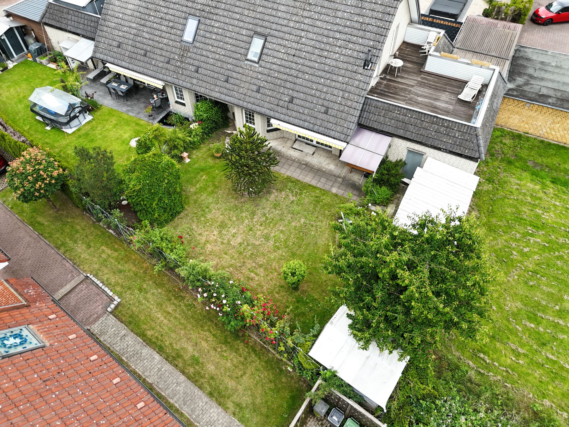 Luftaufnahme eines Hauses mit großem Garten, Terrasse und mehreren Bäumen.