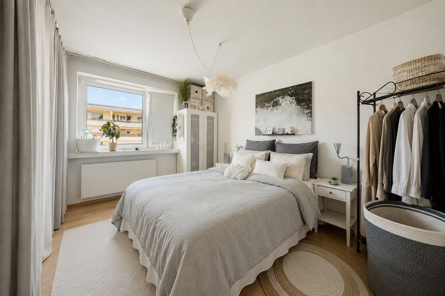 Helles Schlafzimmer mit Doppelbett, Fenster, Kleiderschrank und Kleiderstange.