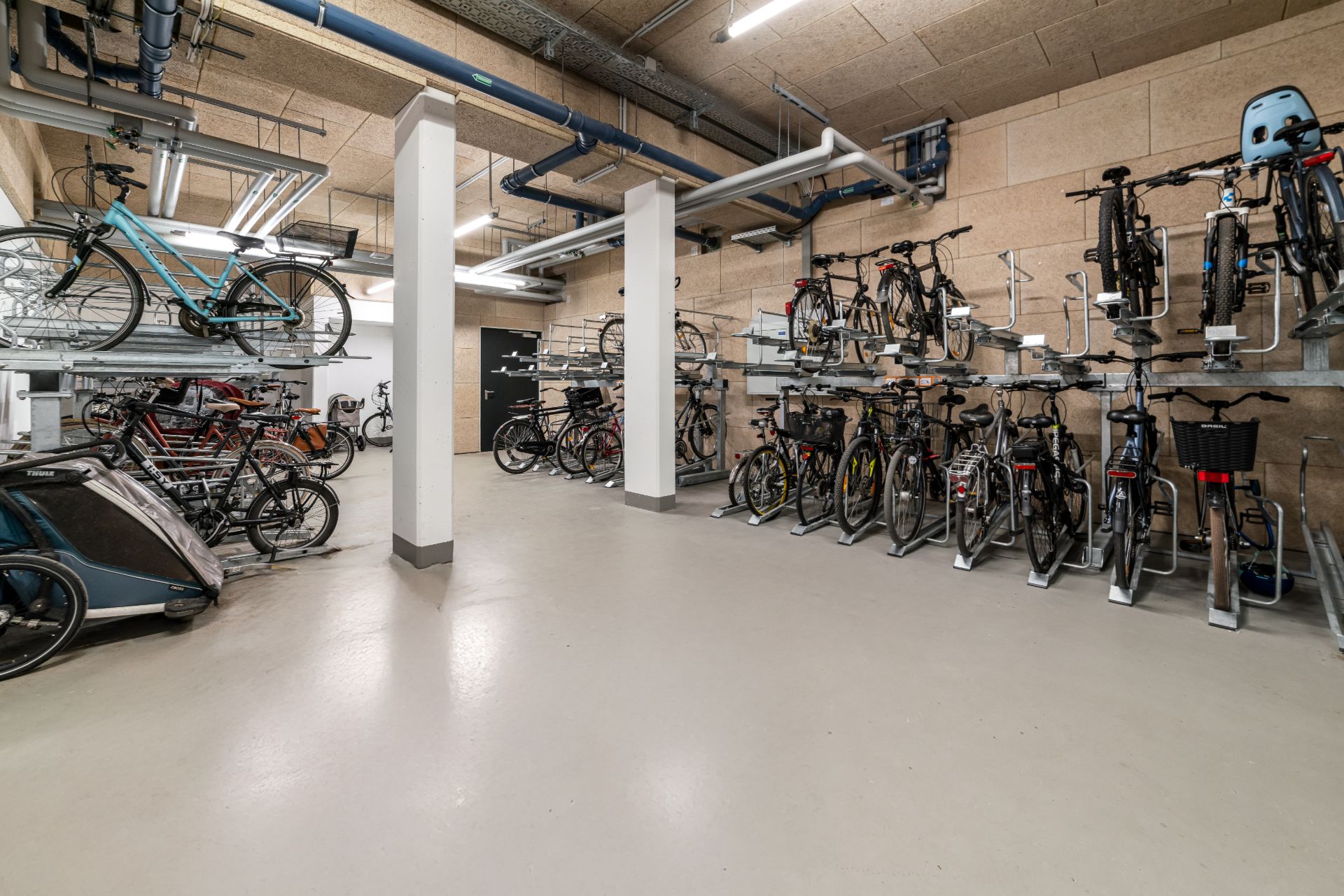 Fahrradraum mit mehreren abgestellten und an Ständern befestigten Fahrrädern.