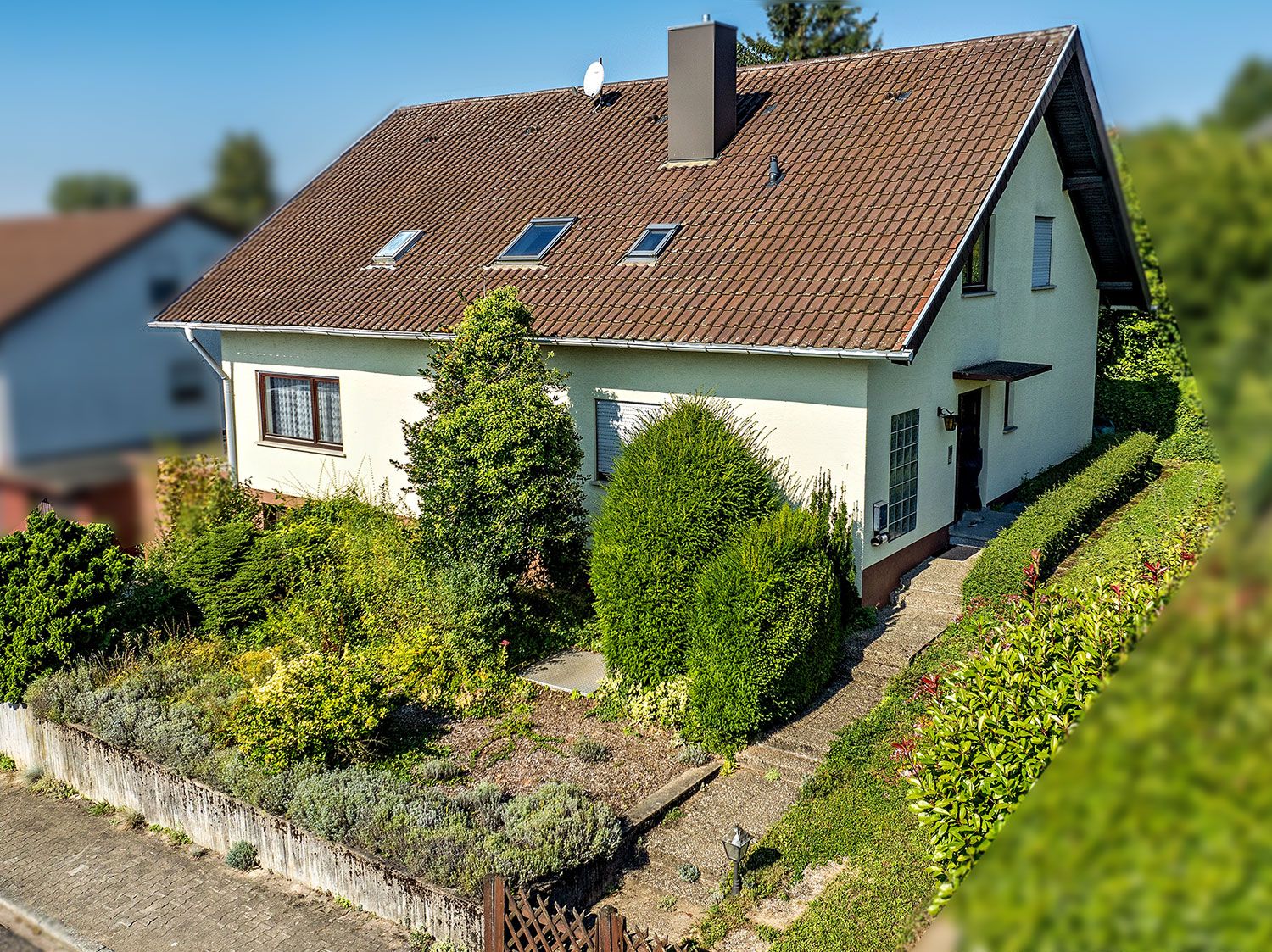 Einfamilienhaus mit Satteldach, Vorgarten und Gehweg zum Eingang.