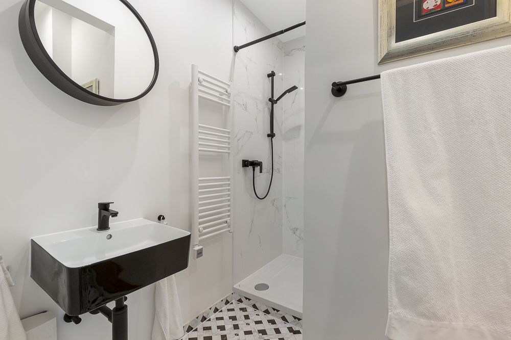 Modernes Badezimmer mit Dusche, Waschbecken, Spiegel und Handtuchhalter.