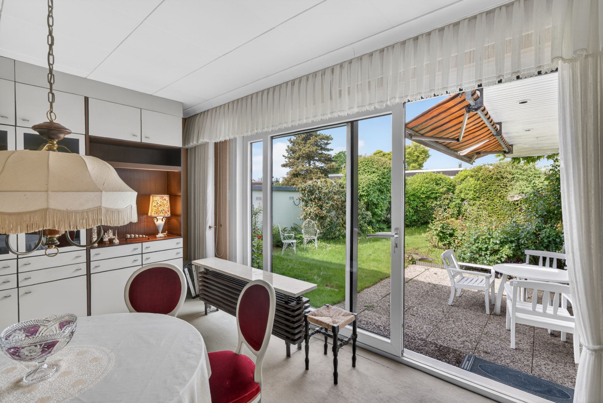 Esszimmer mit Glastür zum Garten und Terrasse mit weißen Gartenmöbeln.