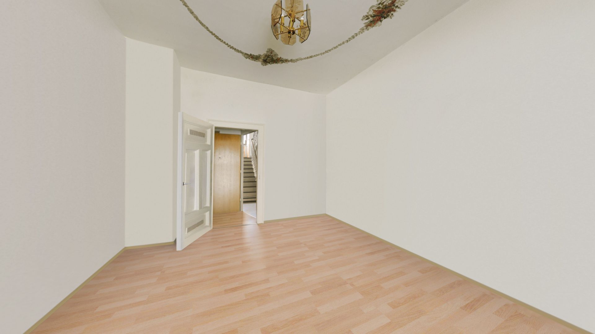 Leerer Raum mit hellem Holzfußboden, weißen Wänden und offener Tür, dahinter eine Treppe.