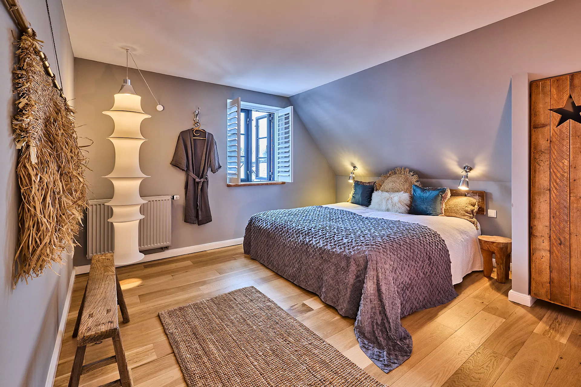 Gemütliches Schlafzimmer mit Doppelbett, Holzboden, Teppich und offenem Fenster.